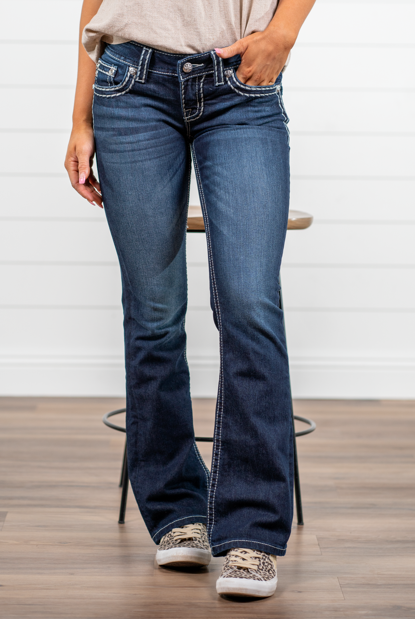 Miss Me Dark wash Bootcut jean with fading, whiskering, and white loose saddle stitching throughout. Jean is detailed with large crystal rivets and antique silver hardware. Inseam: 32" Boot Cut Wash: Dark Blue Low Rise, 7.5" Front Rise Silver Buttons and Rivets 73% Cotton; 25% Polyester; 2% Elastane Style #: JS5014B58V Contact us for any additional measurements or sizing. *Measured on the smallest size, measurements may vary by size.