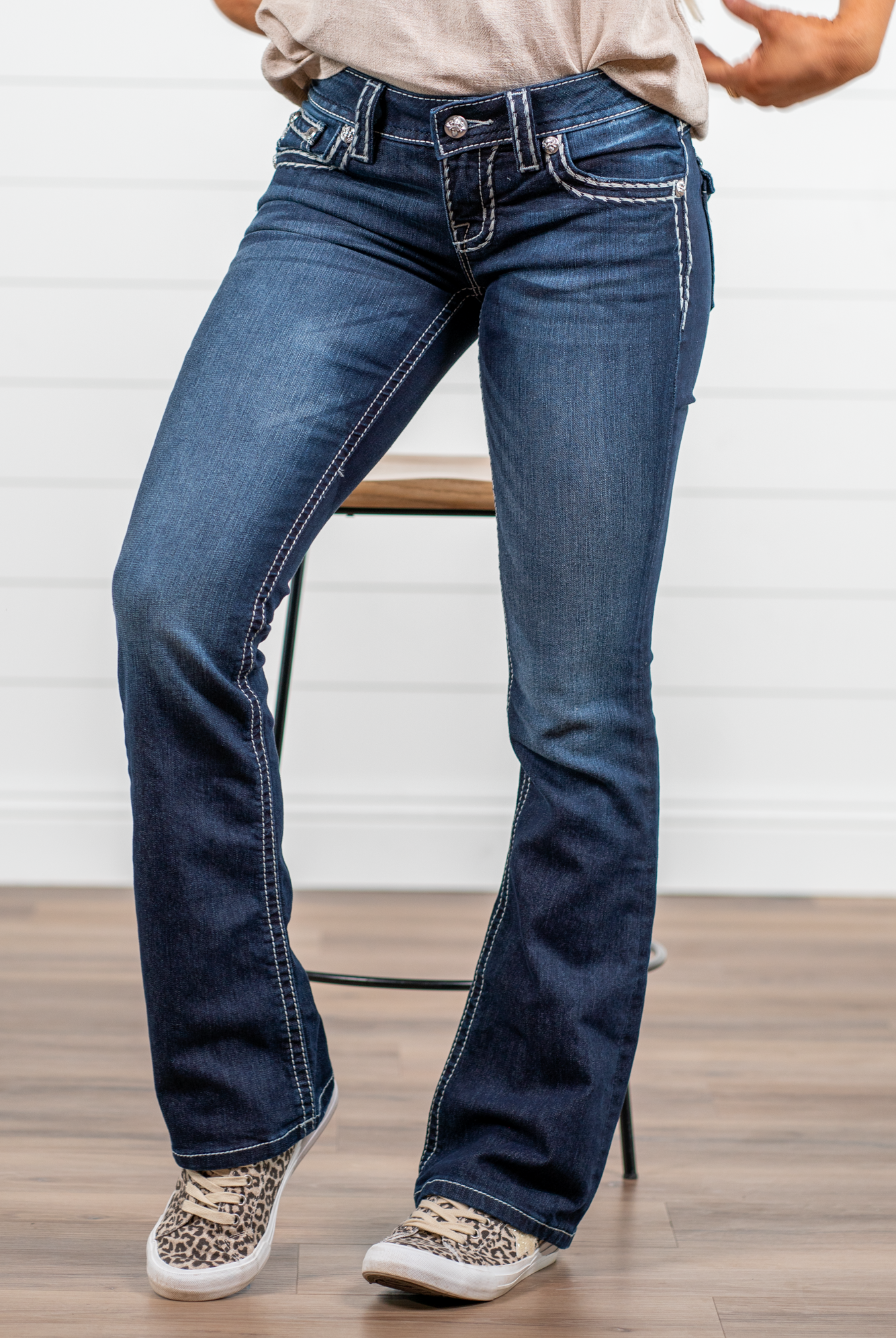 Miss Me Dark wash Bootcut jean with fading, whiskering, and white loose saddle stitching throughout. Jean is detailed with large crystal rivets and antique silver hardware. Inseam: 32" Boot Cut Wash: Dark Blue Low Rise, 7.5" Front Rise Silver Buttons and Rivets 73% Cotton; 25% Polyester; 2% Elastane Style #: JS5014B58V Contact us for any additional measurements or sizing. *Measured on the smallest size, measurements may vary by size.