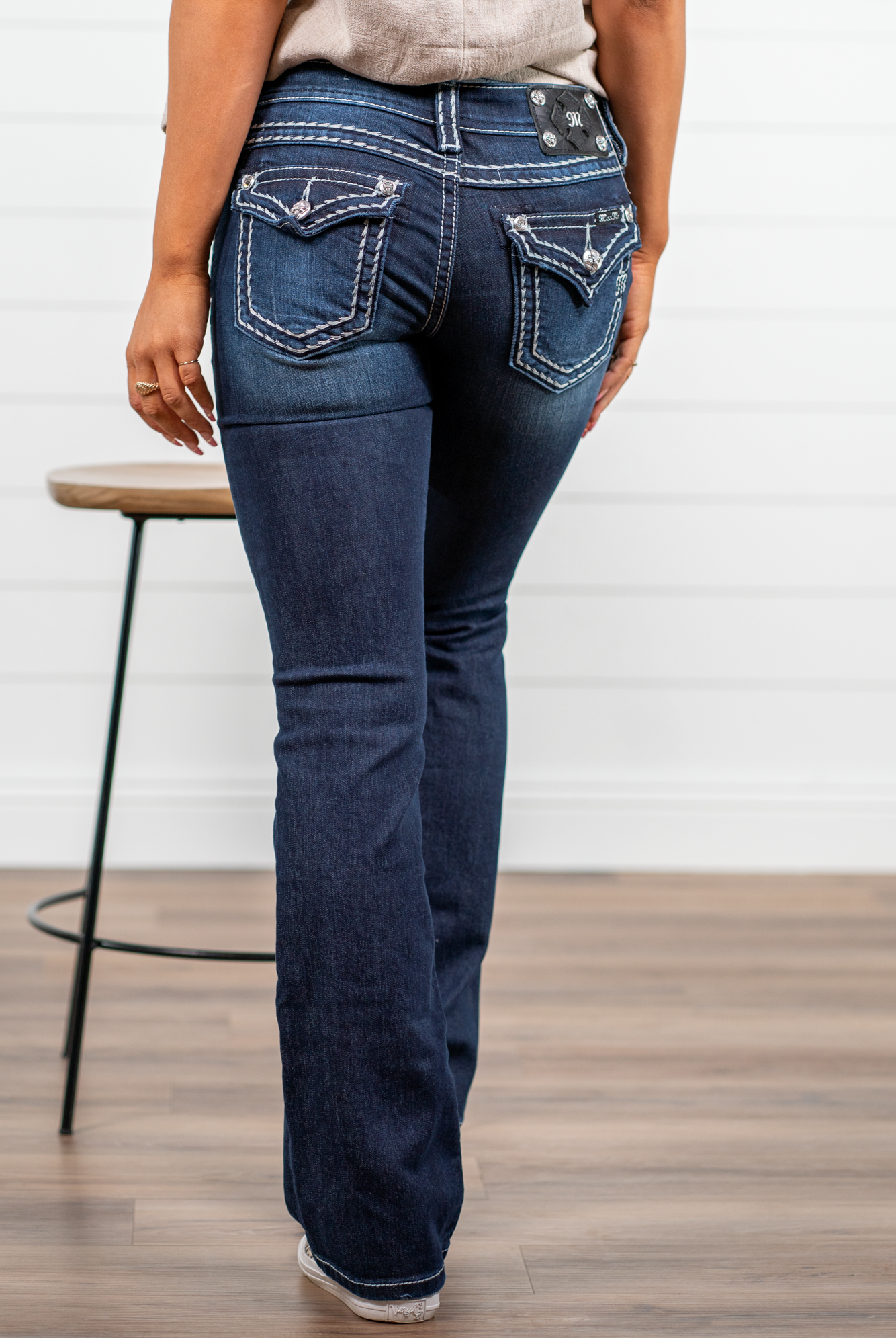 Miss Me Dark wash Bootcut jean with fading, whiskering, and white loose saddle stitching throughout. Jean is detailed with large crystal rivets and antique silver hardware. Inseam: 32" Boot Cut Wash: Dark Blue Low Rise, 7.5" Front Rise Silver Buttons and Rivets 73% Cotton; 25% Polyester; 2% Elastane Style #: JS5014B58V Contact us for any additional measurements or sizing. *Measured on the smallest size, measurements may vary by size.