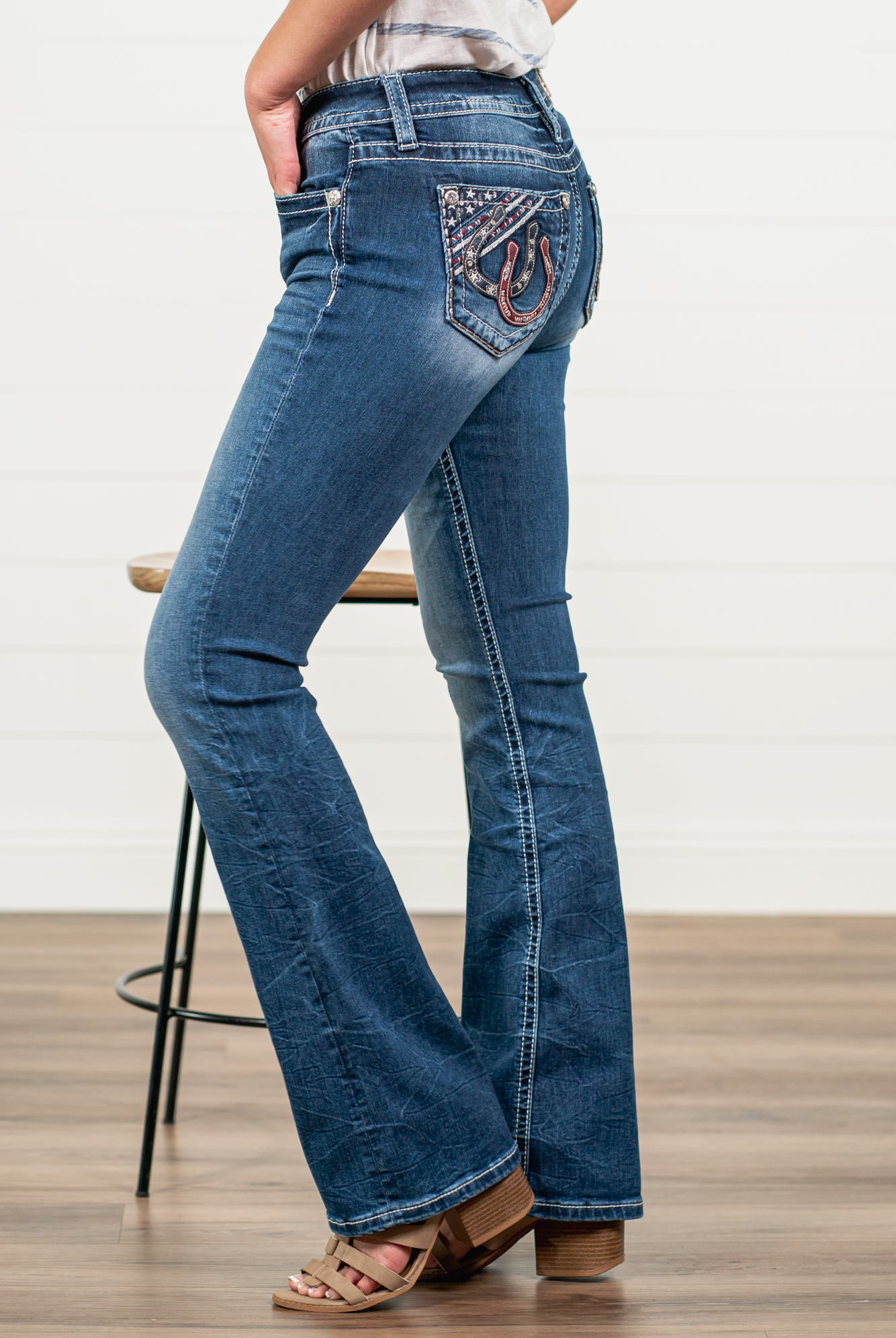 Miss Me Stay sassy and sweet in this bootcut detailed with whiskering, distressing, and embroidered back pocket with rhinestone rivets. Wear these every day to bling up your wardrobe. Wash: Medium Blue Inseam: 34" Boot Cut* Mid Rise, 9" Front Rise* Silver Buttons and Rivets Bright Clear Crystals Fading & Whiskering Details 91% Cotton 6% Polyester 3% Elastane Style #: M3845B Contact us for any additional measurements or sizing. *Measured on the smallest size, measurements may vary by size.