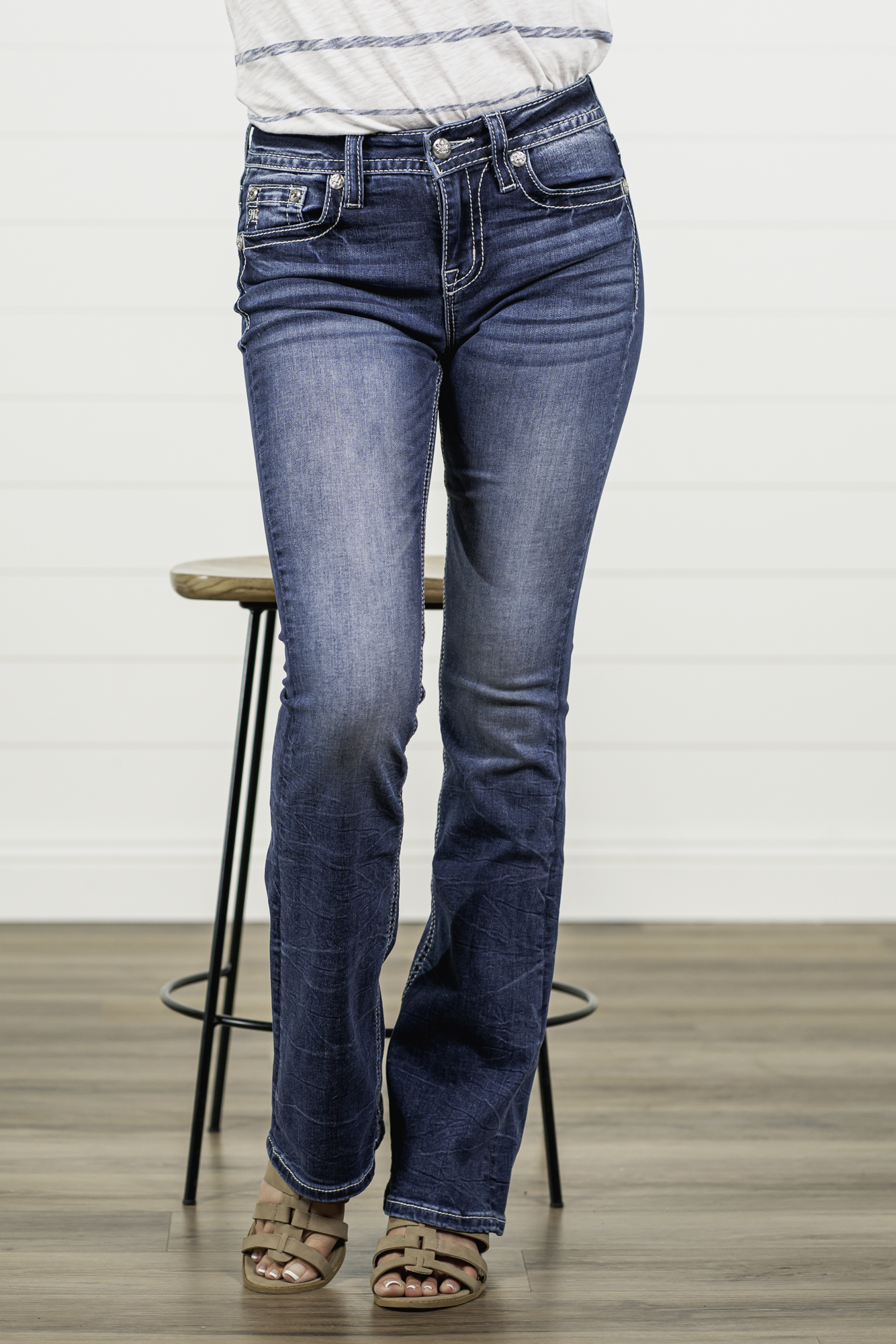 Miss Me Stay sassy and sweet in this bootcut detailed with whiskering, distressing, and embroidered back pocket with rhinestone rivets. Wear these every day to bling up your wardrobe. Wash: Medium Blue Inseam: 34" Boot Cut* Mid Rise, 9" Front Rise* Silver Buttons and Rivets Bright Clear Crystals Fading & Whiskering Details 91% Cotton 6% Polyester 3% Elastane Style #: M3845B Contact us for any additional measurements or sizing. *Measured on the smallest size, measurements may vary by size.