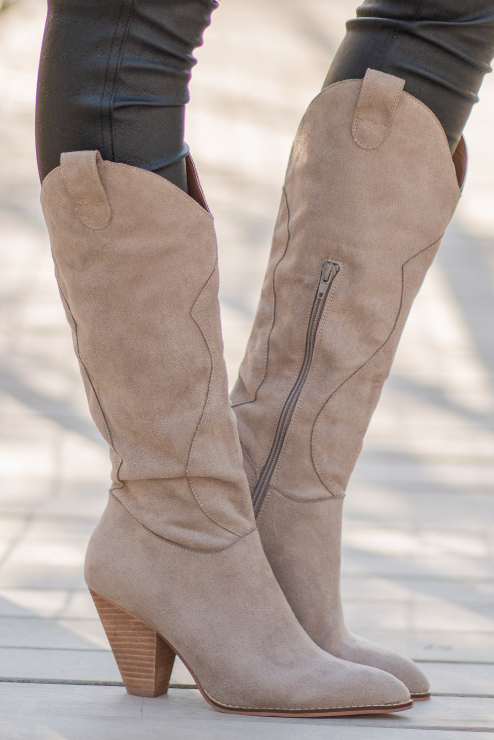Boots by Mi.iM A western knee high boot with a zipper and block heel with a v cut to elongate the legs. Color: Taupe Man-made Upper Leather Wrap heel Padded footbed Shaft Height: 12" Heel Height: 3.5" Contact us for any additional measurements or sizing.