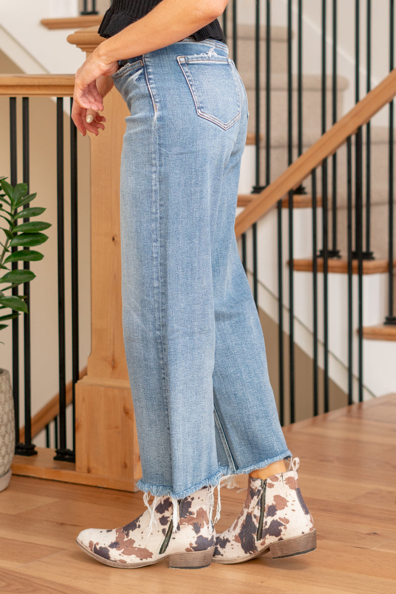 Flying Monkey  The Sophia High Rise Wide Leg Jeans featuring a trendy raw hem. These jeans offer a flattering high-rise silhouette and a wide leg for a perfect blend of style and comfort. The raw hem adds a touch of edge, making them a versatile choice for both casual and dressed-up looks.