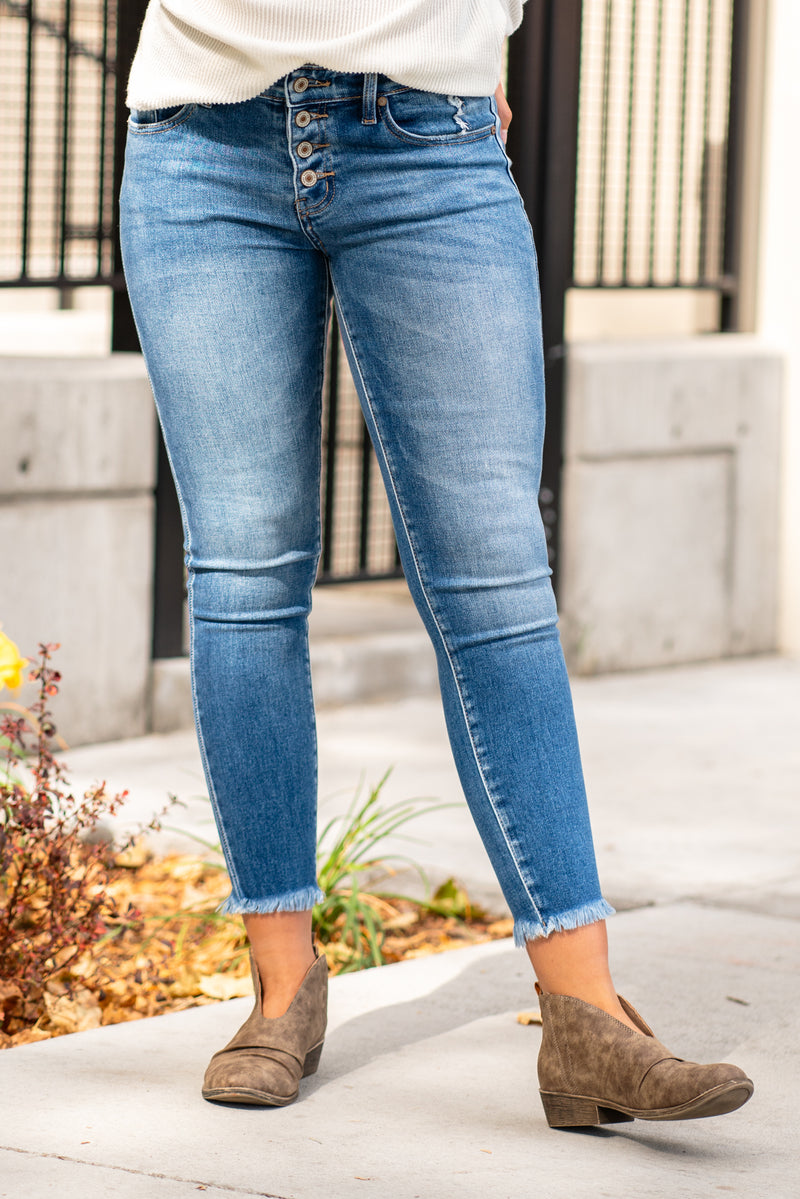 KanCan Jeans  KanCan Stretchy with an asymmetrical waistband and frayed hem.   Color: Medium Wash Cut: Ankle Skinny, 27" Inseam* Rise: High-Rise, 9" Front Rise* 93% COTTON , 5% POLYESTER , 2% SPANDEX Fly: Zipper  Style #: KC6381M Contact us for any additional measurements or sizing.   *Measured on the smallest size, measurements may vary by size. 