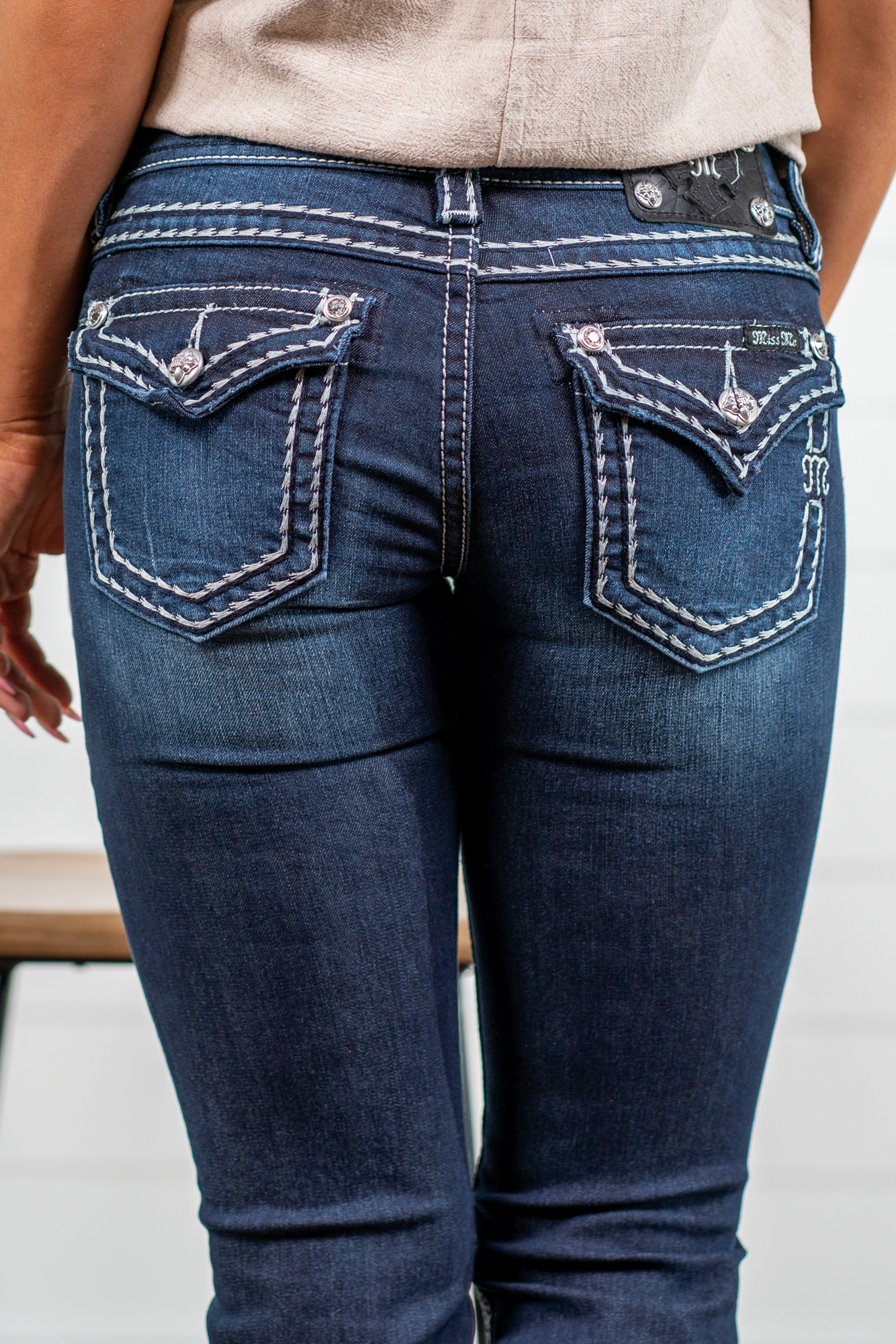 Miss Me  Dark wash Bootcut jean with fading, whiskering, and white loose saddle stitching throughout. Jean is detailed with large crystal rivets and antique silver hardware.  Inseam: 32" Boot Cut Wash: Dark Blue Low Rise, 7.5" Front Rise Silver Buttons and Rivets  73% Cotton; 25% Polyester; 2% Elastane Style #: JS5014B58V Contact us for any additional measurements or sizing.  *Measured on the smallest size, measurements may vary by size. 