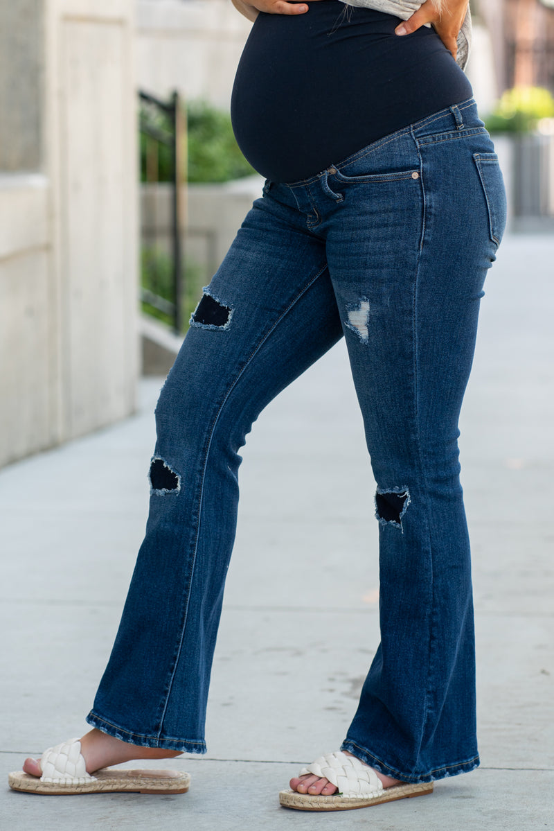 KanCan Maternity Jeans  Do you miss wearing jeans? These maternity jeans will keep you comfy and cute with an elastic stretch waistband that fits over the tummy.   Color: Dark Blue Wash Ripped Distressed Denim Patched Legs Fray Hem Detail Cut: Flare, 30" Inseam Rise: Mid-Rise with Full Tummy Band, 5.5" Material: 94% COTTON, 4% T-400, 2% SPANDEX Style #: KC3014D Contact us for any sizing questions or measurements.
