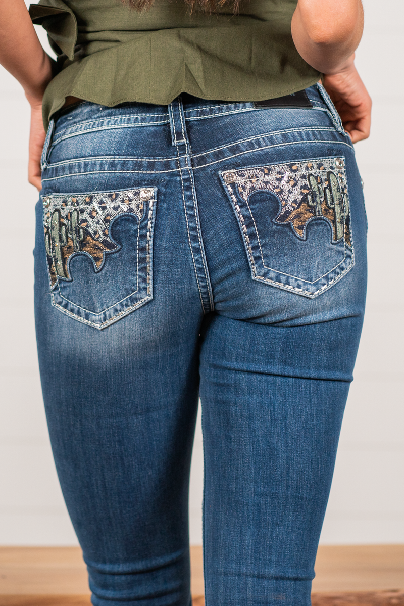 Miss Me  Wear these leopard cactus embellished pocket jeans every day to bling up your wardrobe. Slim boot cut jeans featuring a 5 pocket design, whiskering, and crystal rivets. Wash: Dark Blue Inseam: 34" Slim Boot Cut* Mid Rise, 8.75" Front Rise* Silver Buttons and Rivets  Style #: M3825B Contact us for any additional measurements or sizing.    *Measured on the smallest size, measurements may vary by size. 